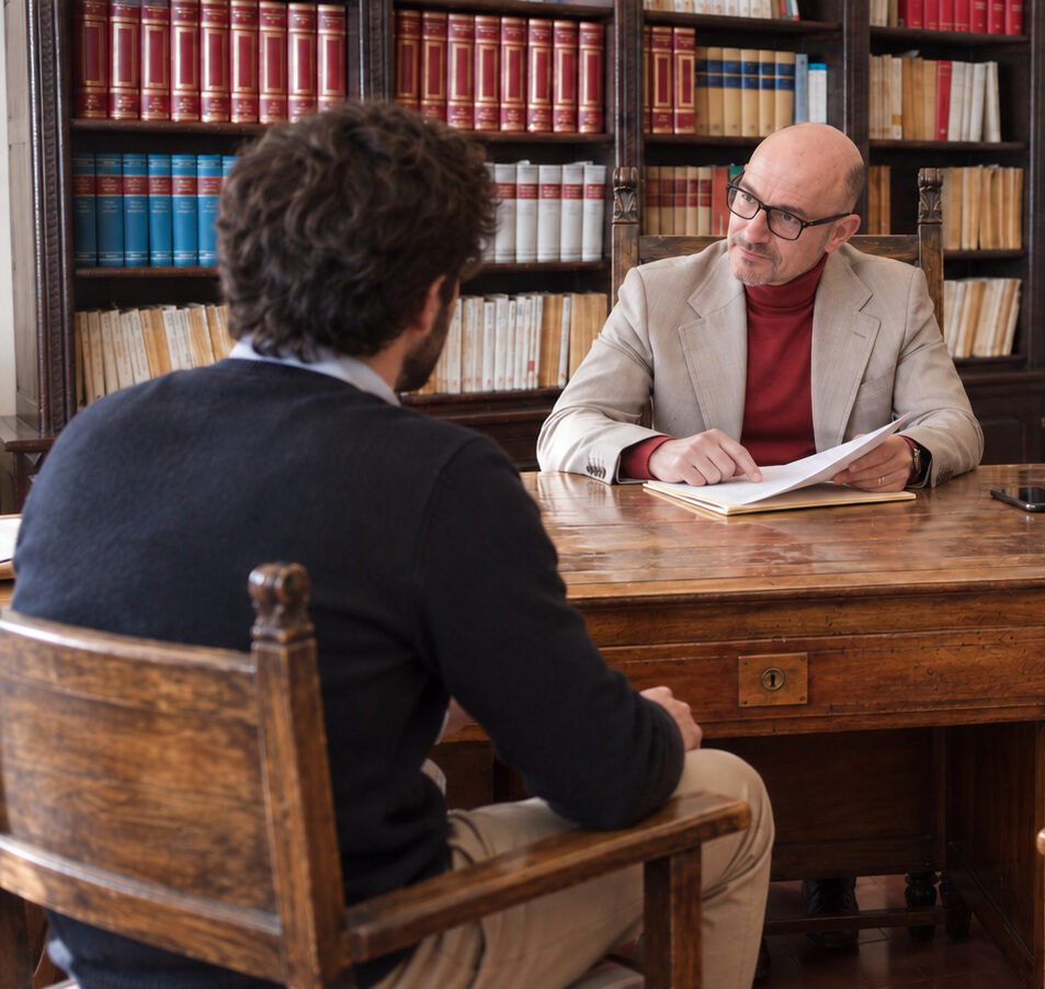 L’avvocato Matteo della Pietra esamina una pratica di diritto penale durante il colloquio con un cliente